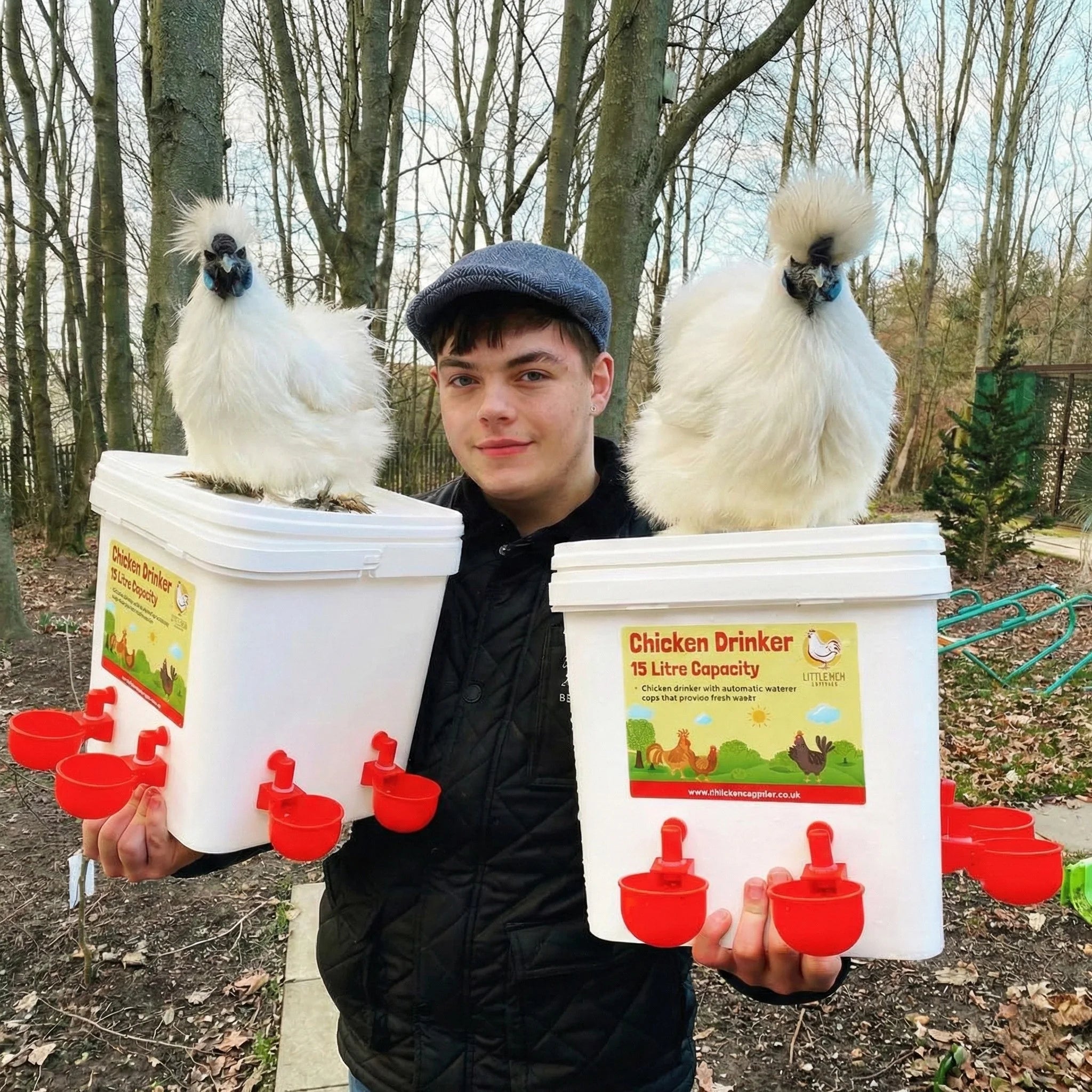 Chicken keeper holding two identical 15 litre chicken drinkers, with silkie chickens standing on top to show real-life use and capacity