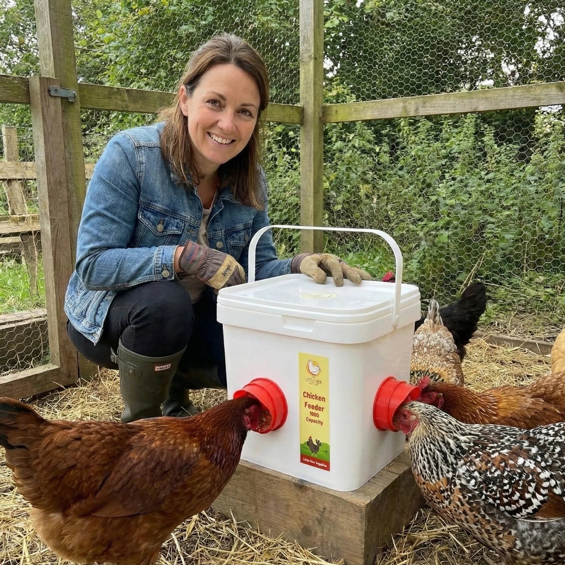 Woman feeding chickens from a white chicken feeder with feeding ports in an outdoor setting.